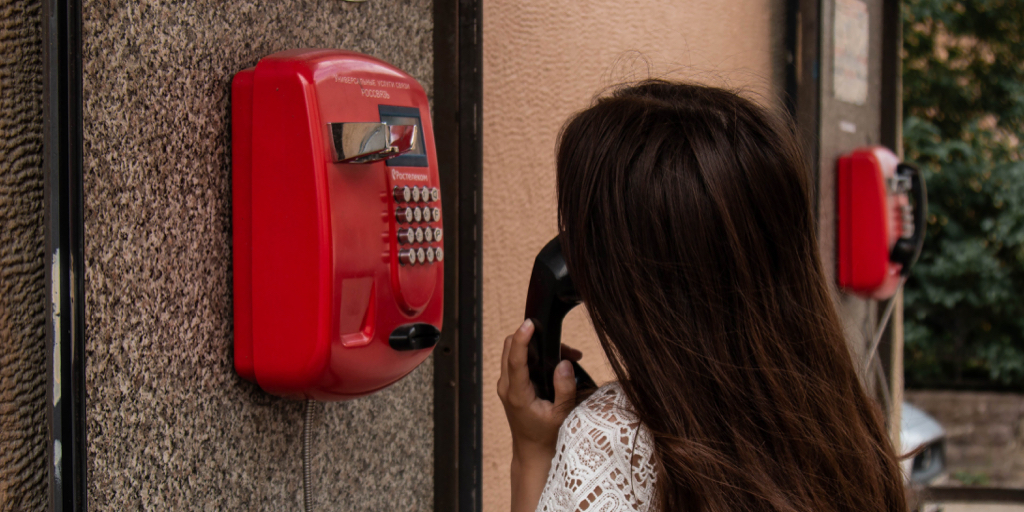 Lady talking on a red pay phone.